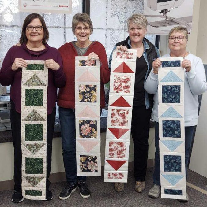 The Women of The Quilt Basket Holding Sample Works